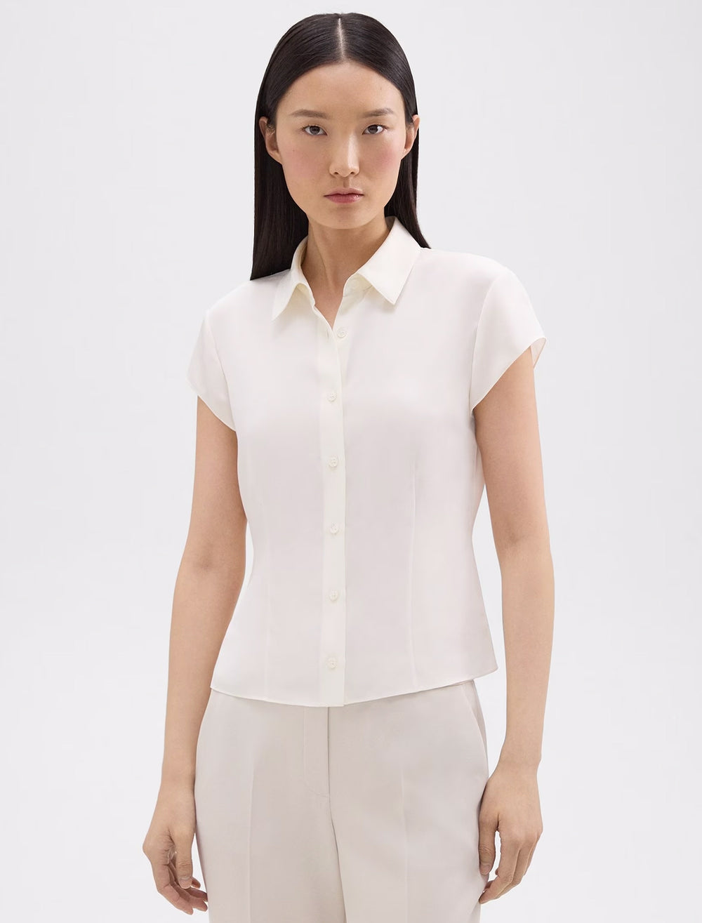Model wearing Theory's cap sleeve blouse in ivory.
