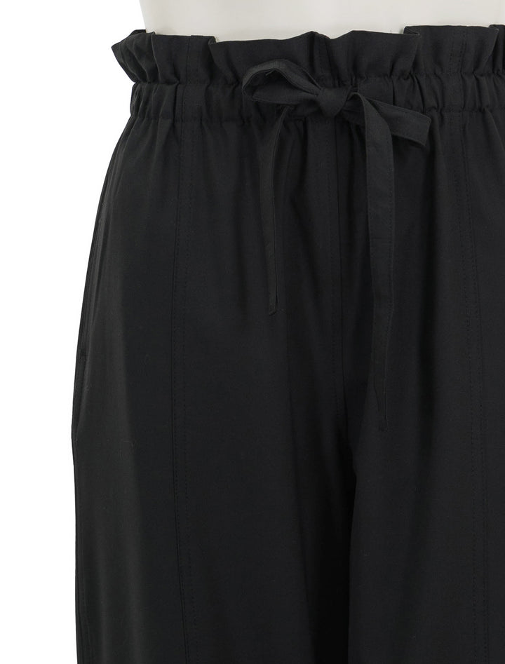 Close-up view of GANNI's drapey melange pants in black.