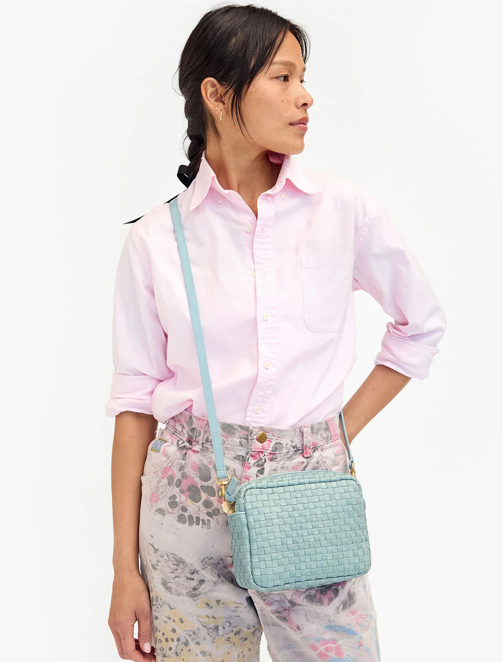 Model wearing Clare V.'s midi sac in sunbleached sky blue woven as a crossbody.