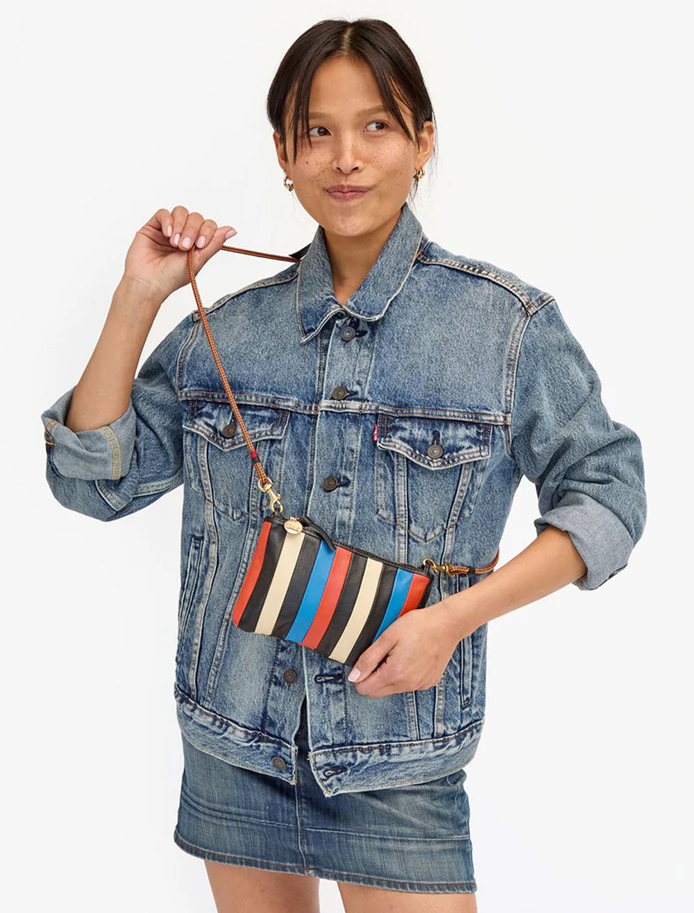 Model wearing Clare V.'s wallet clutch with tabs in multi stripe nappa as a crossbody.