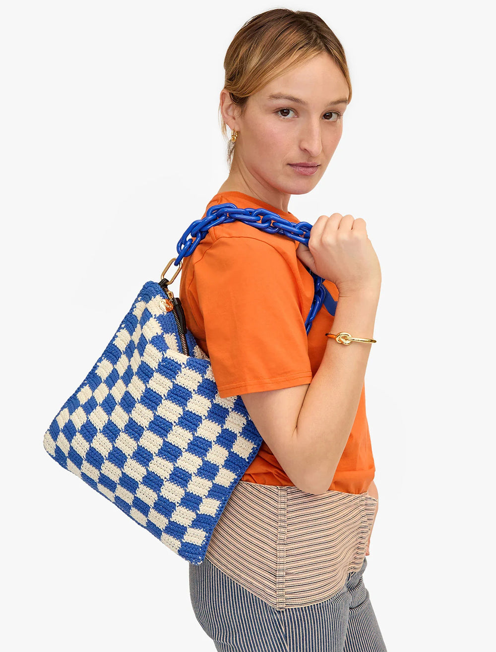 Model wearing Clare V.'s foldover clutch with tabs in cobalt and cream crochet checker with a strap.