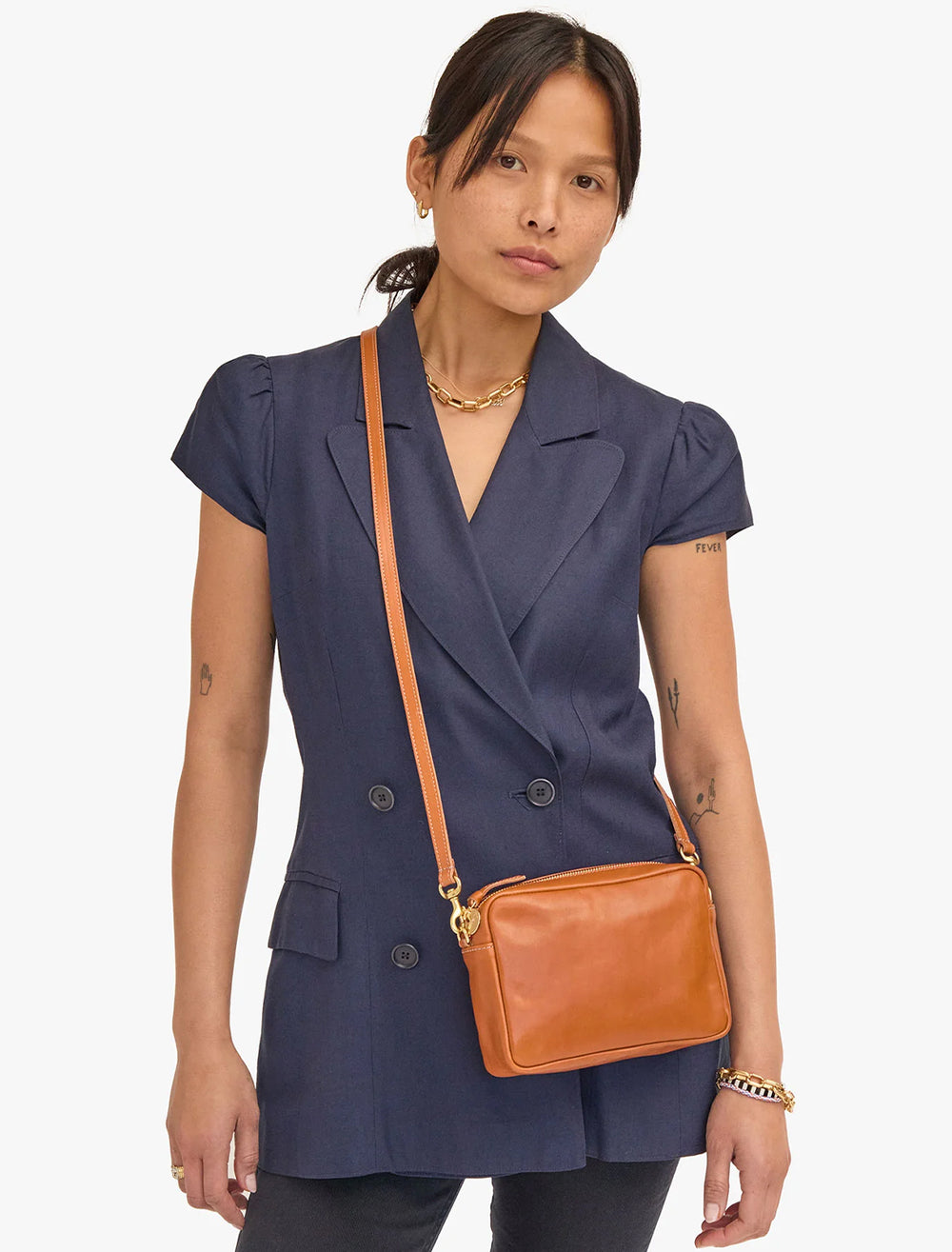 Model wearing Clare V.'s midi sac in tan nepetto as a crossbody.