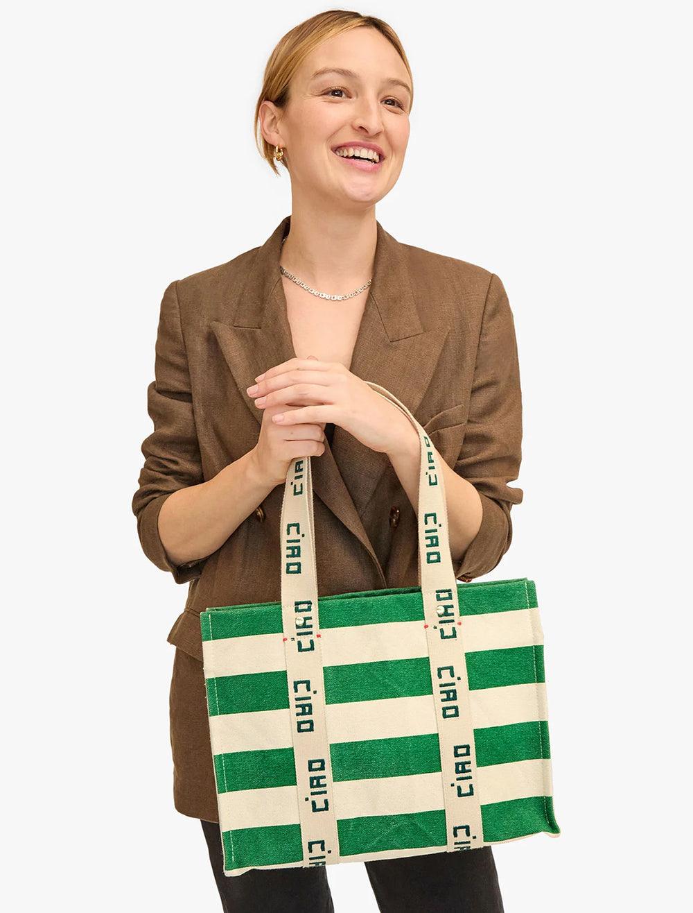 Model carrying Clare V.'s noemie tote in palm green and natural stripe.