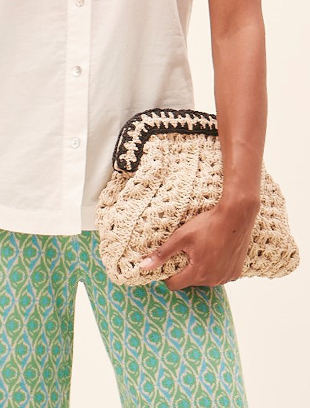 Model carrying Suncoo Paris' Arvel Clutch in Natural and Black Raffia.