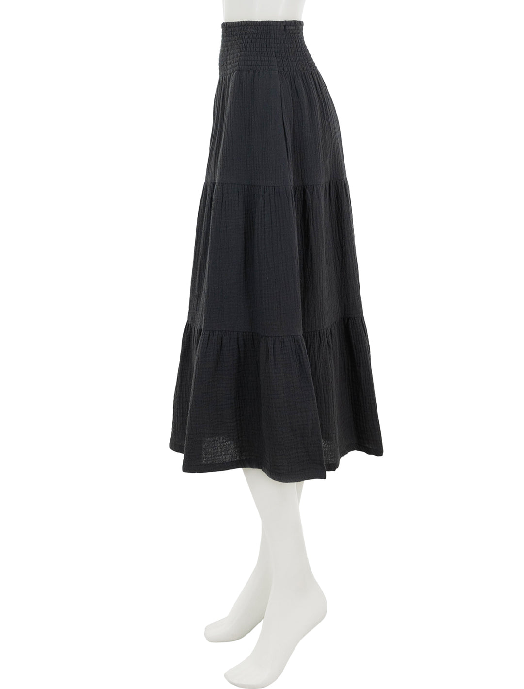 Side view of marine layer's corinne smocked waist maxi skirt in black.