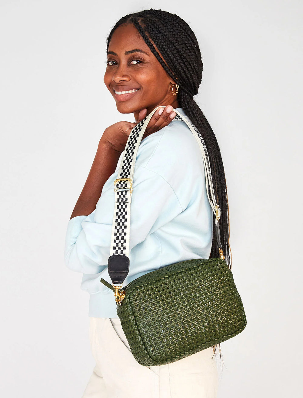 Model wearing Clare V.'s adjustable crossbody strap in black and cream checker attached to a bag