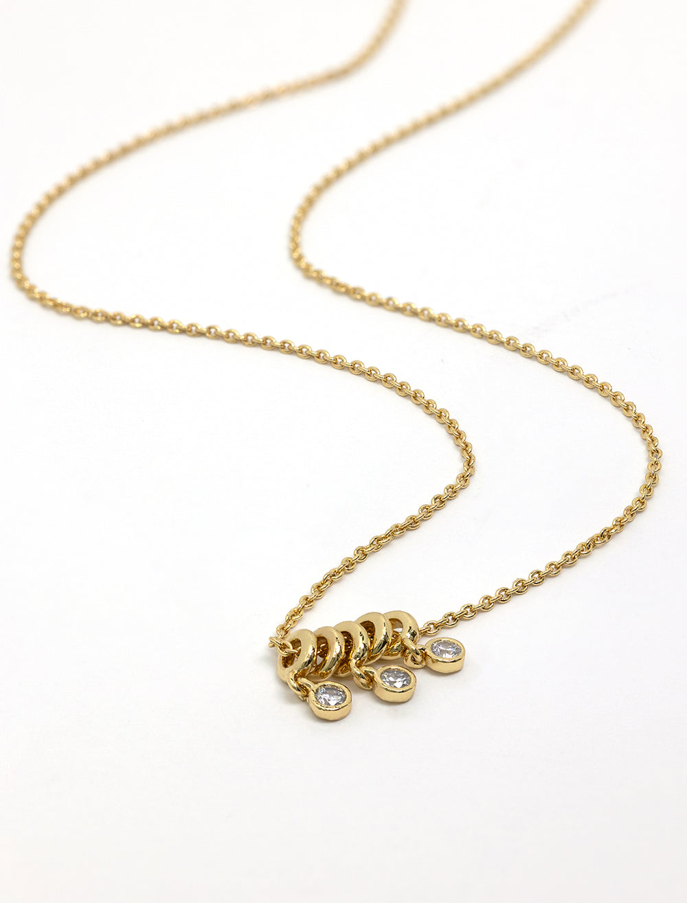 Stylized laydown of Tai's necklace with gold rings and cz dangles.