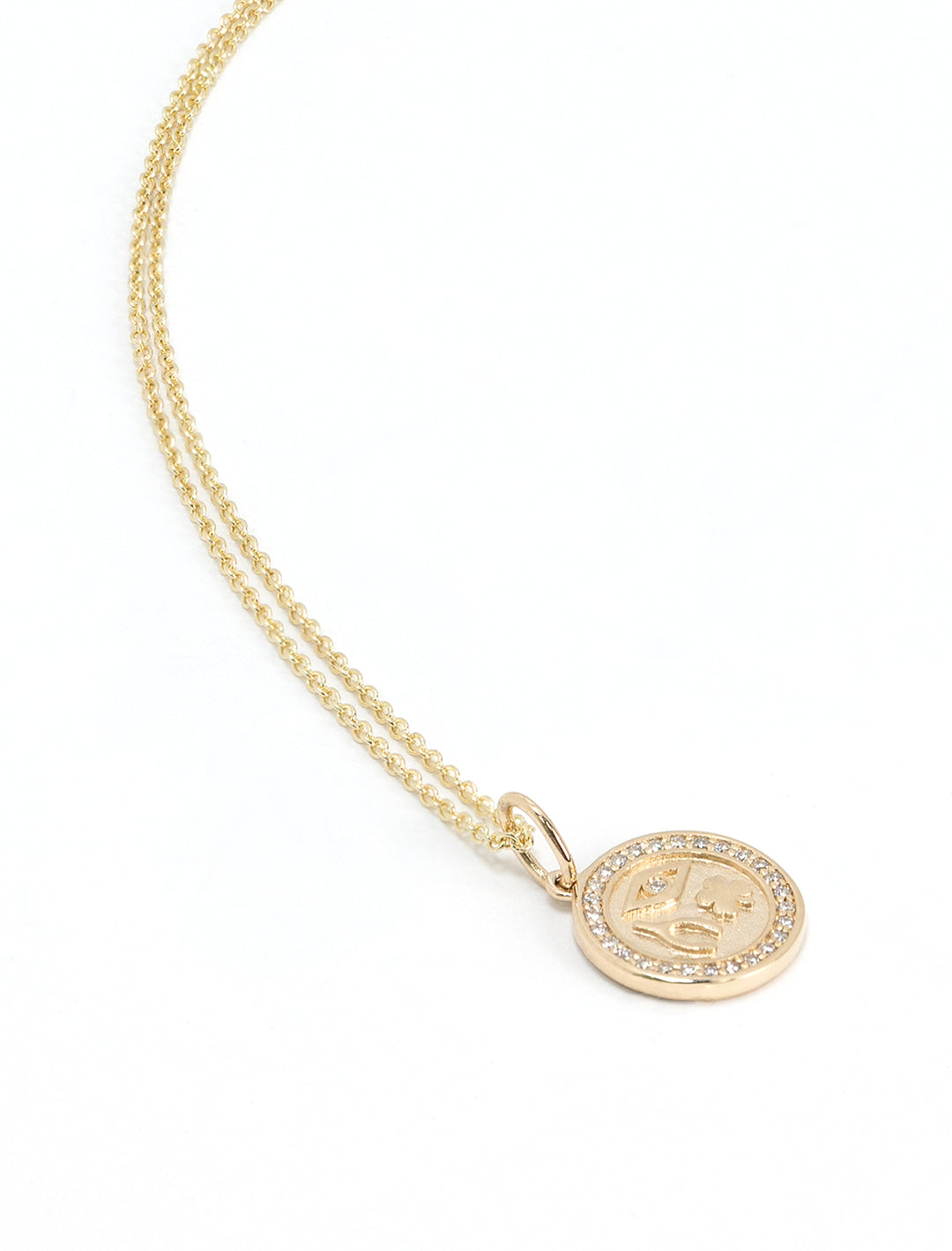 Stylized laydown of Sydney Evan's Luck and Protection Pave Border Medallion Necklace.