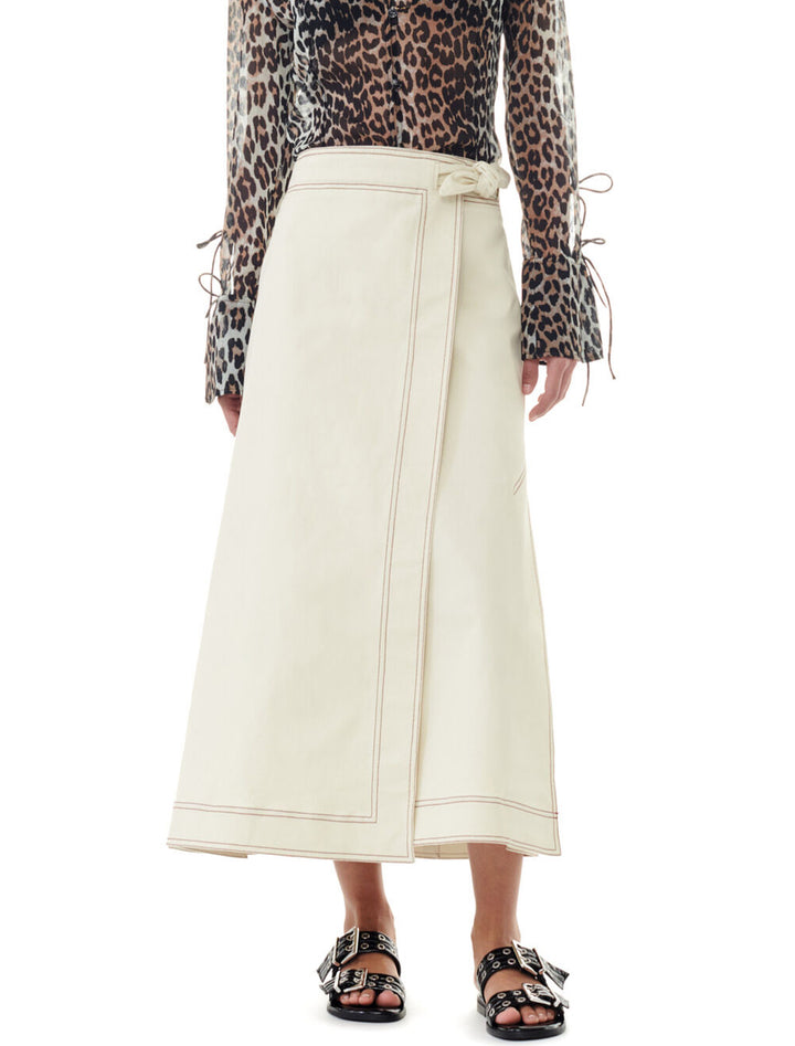 Model wearing GANNI's herringbone canvas long wrap skirt in summer sand.