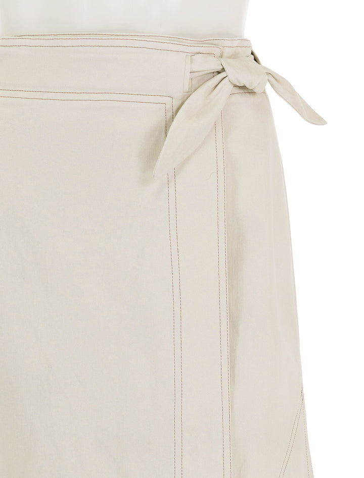 Close-up view of GANNI's herringbone canvas long wrap skirt in summer sand.