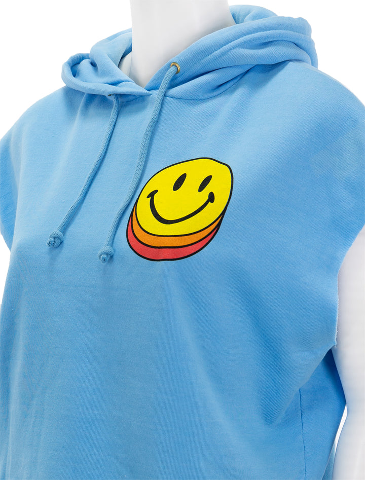 Close-up view of Aviator Nation's smiley sunset sleeveless cropped pullover hoodie in sky.