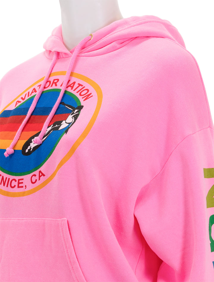 Close-up view of Aviator Nation's pullover hoodie relaxed in neon pink.