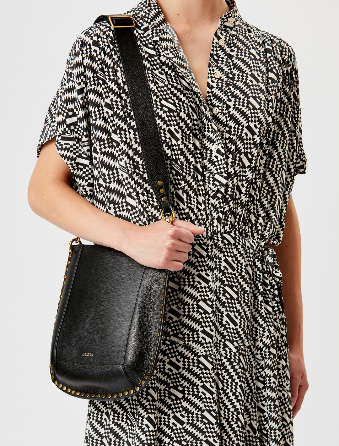 Model wearing Isabel Marant Etoile's oksan grained leather shoulder bag in black on her shoulder.