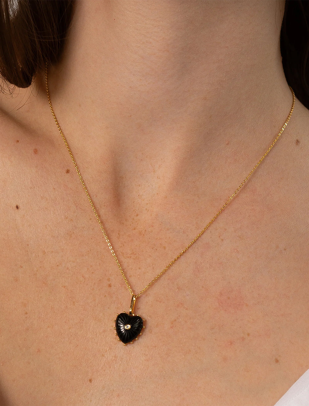 Model wearing THATCH's isabel onyx heart necklace in gold.