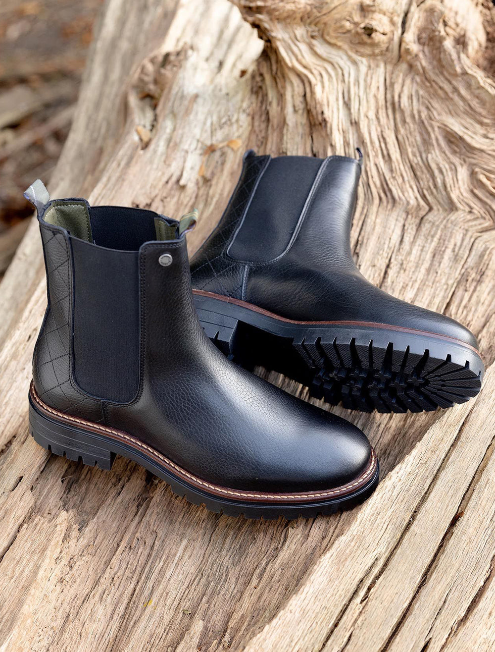 Stylized laydown of Barbour's evie chelsea boot in black pebble.