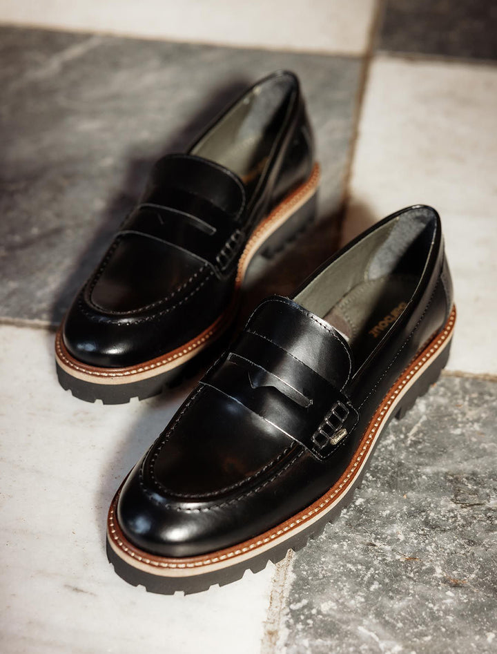 Stylized laydown of Barbour's ludlow penny loafer in black polido.