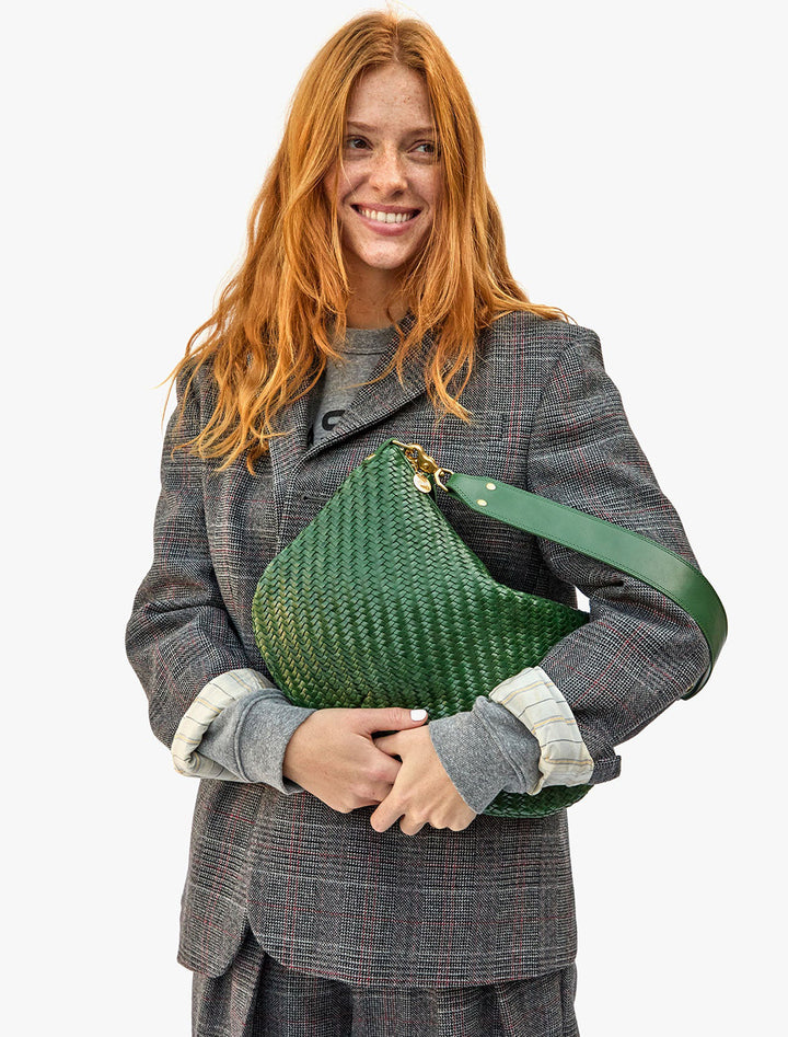 Model carrying Clare V.'s moyen messenger in evergreen woven zig zag.