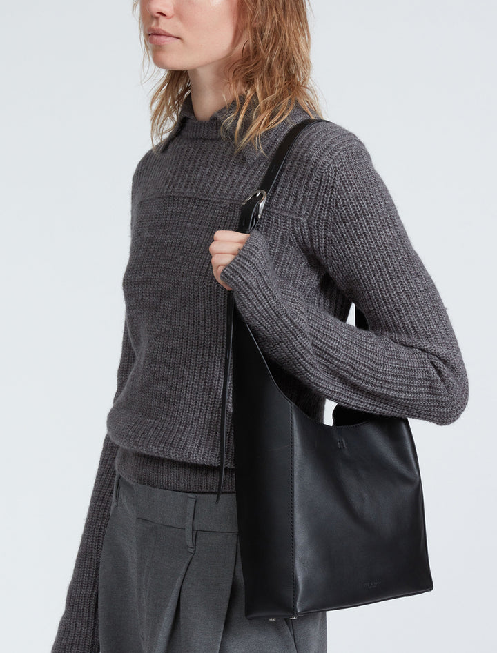 Model wearing Rag & Bone's belize small shopper in black on her shoulder.