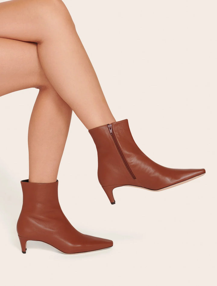 Model wearing Staud's wally ankle boot in cacao.