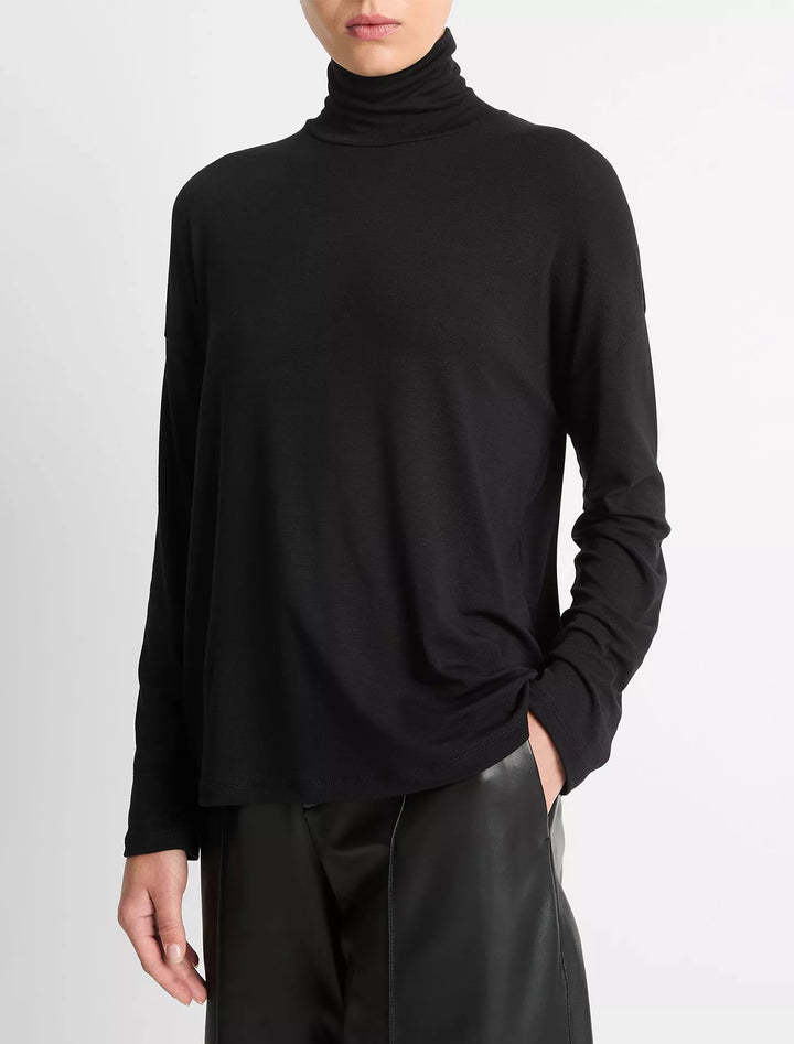 Model wearing Vince's relaxed long sleeve turtleneck in black.