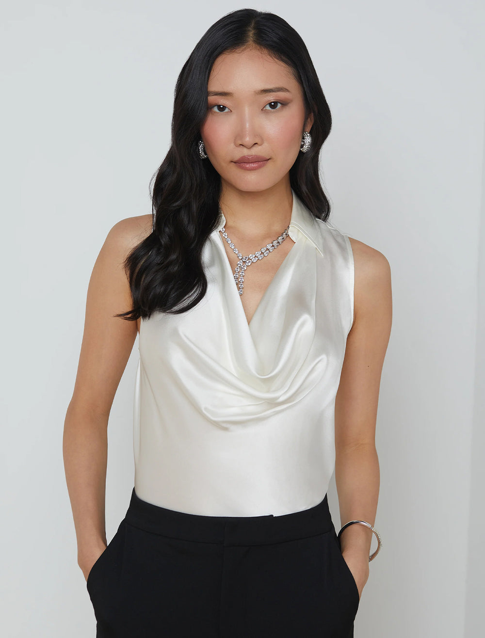 Model wearing L'Agence's colter cowlneck sleeveless blouse in ivory.