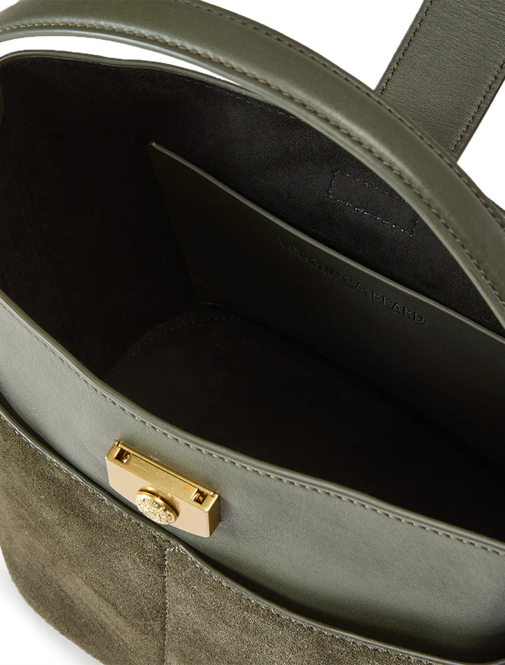 Close-up inside view of Veronica Beard's the small crest lock bucket bag in pine.