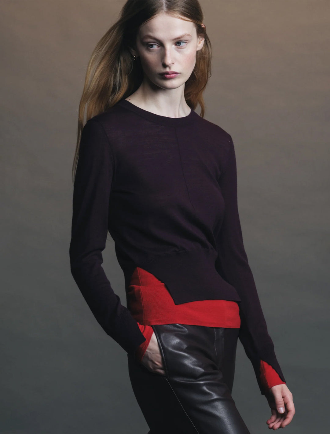 Model wearing Saint Art's myra layered sweater in burgundy and tomato.