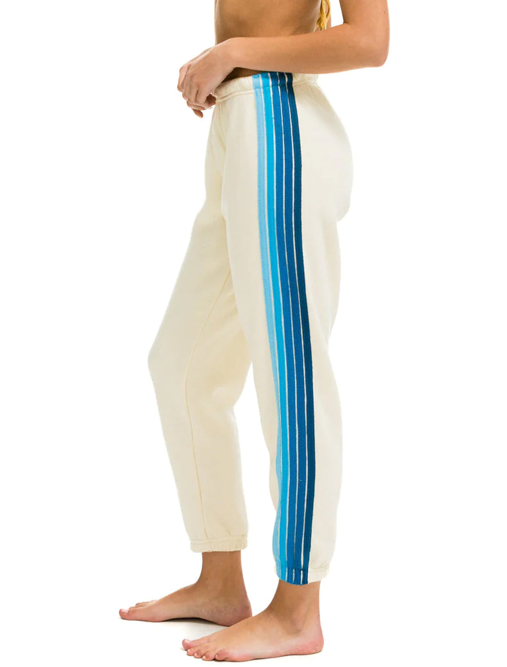 Model wearing Aviator Nation's 5 stripe womens sweatpants in vintage white and blue.