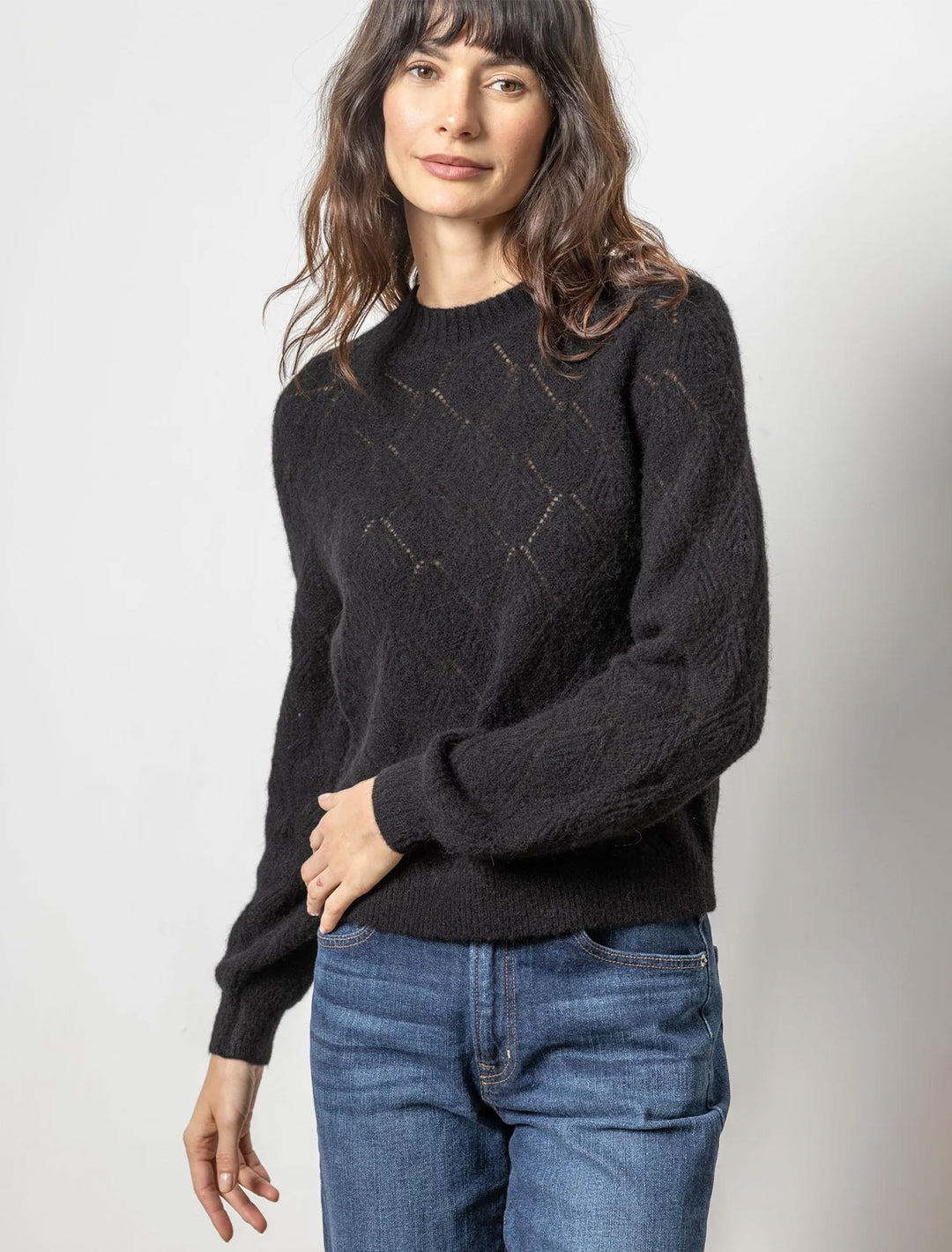 Model wearing Lilla P.'s easy pointelle crewneck sweater in black.