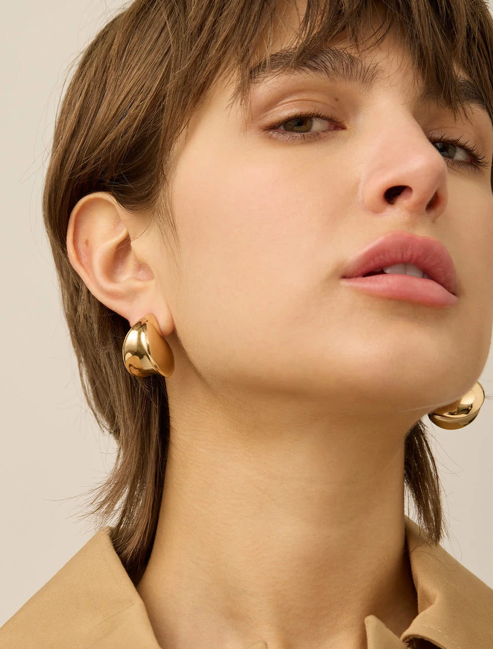 Model wearing Jenny Bird's nouveaux puff earrings in gold.