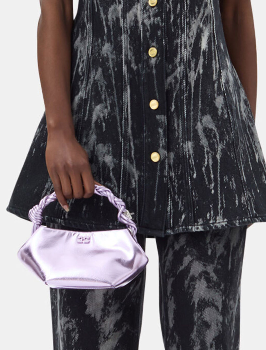 Model holding GANNI's mini bou bag in pink lavender metallic.