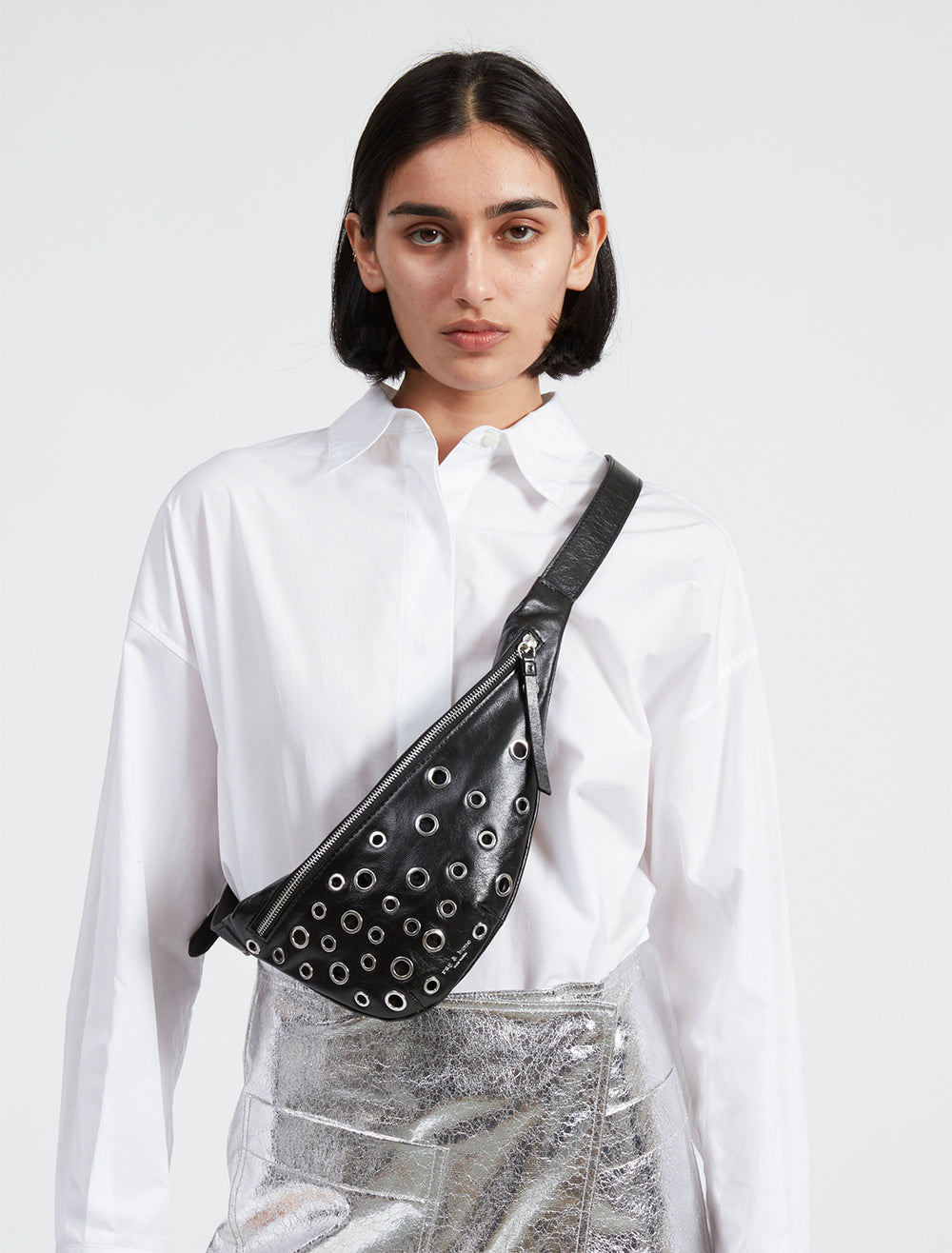 Model wearing Rag & Bone's petra mini sling with grommets in black across her body.