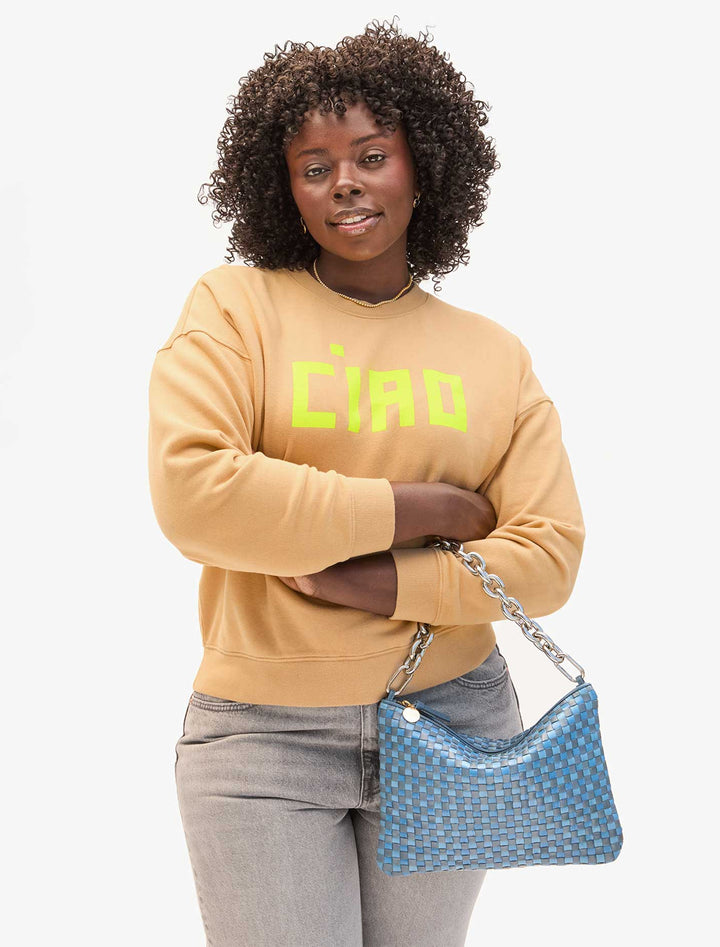 model holding flat clutch with tabs in light blue woven checker