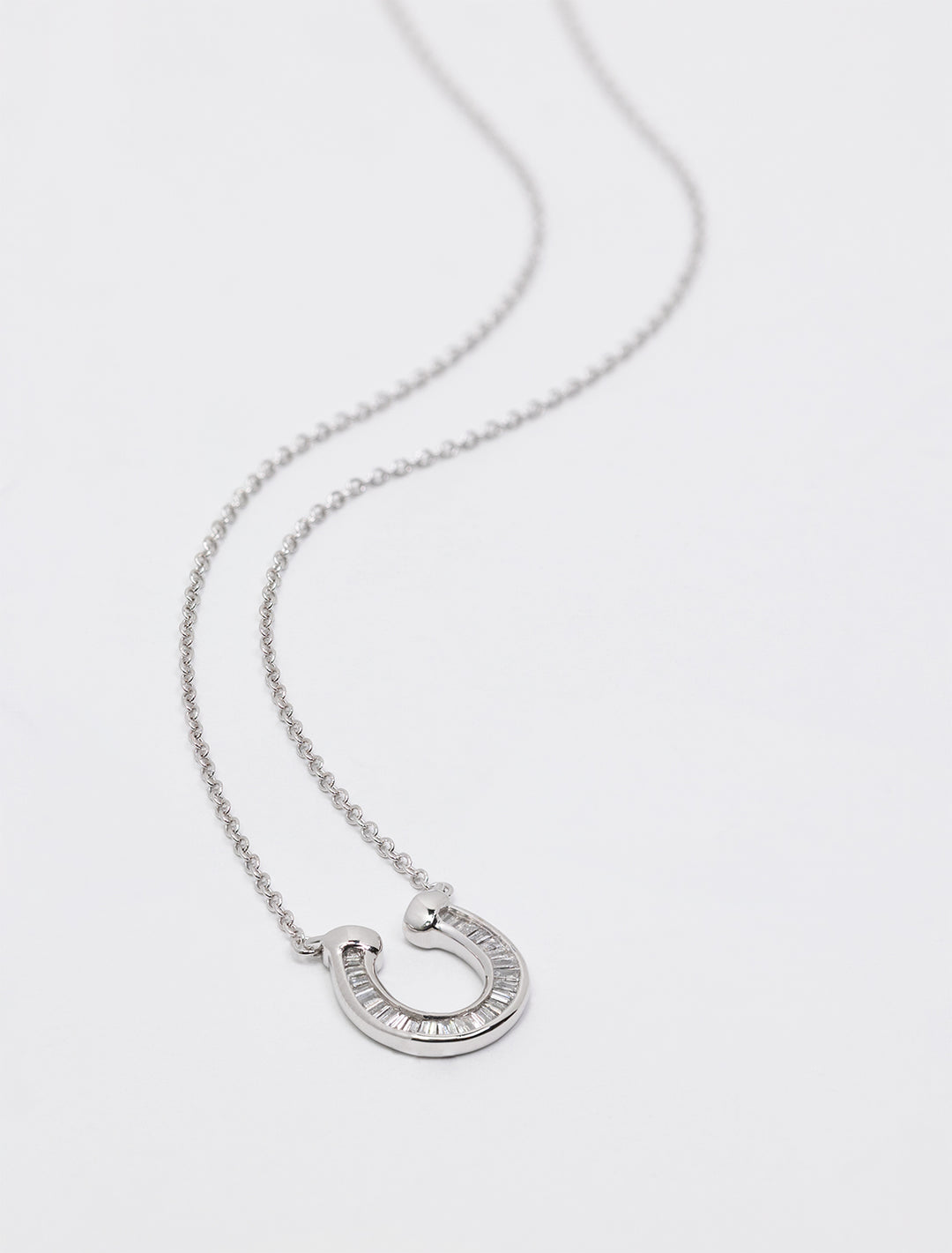 Close-up view of Adina Reyter's baguette horseshoe necklace in silver.