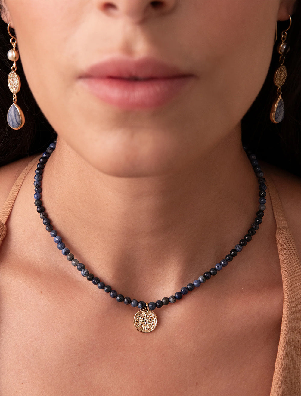 Model wearing Anna Beck's dumortierite beaded necklace with medium gold pendant.