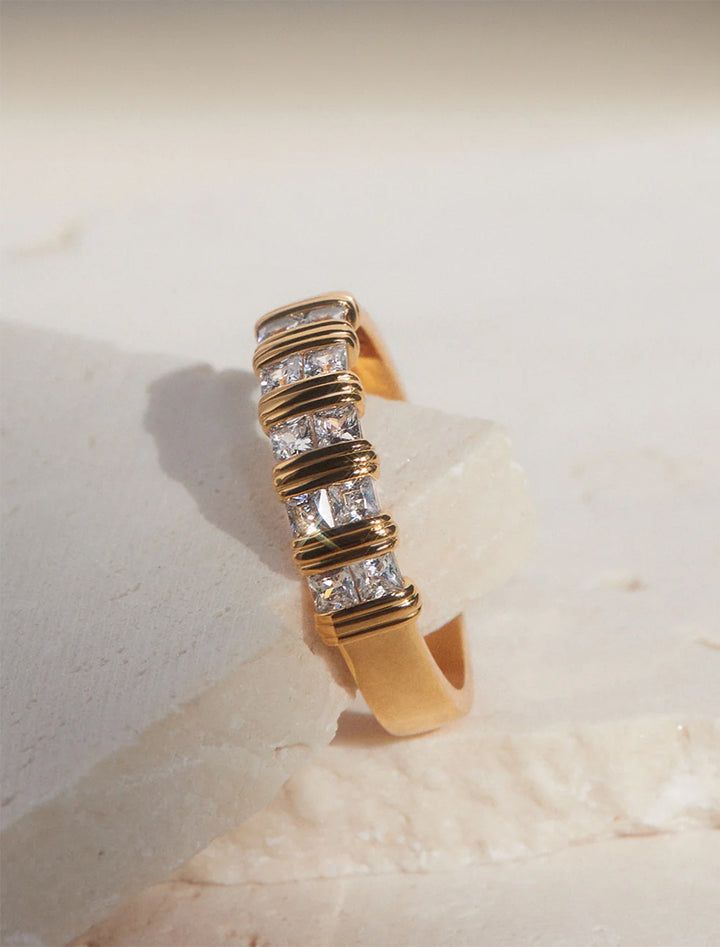 Stylized laydown of LUV AJ's remy princess cut band in gold.