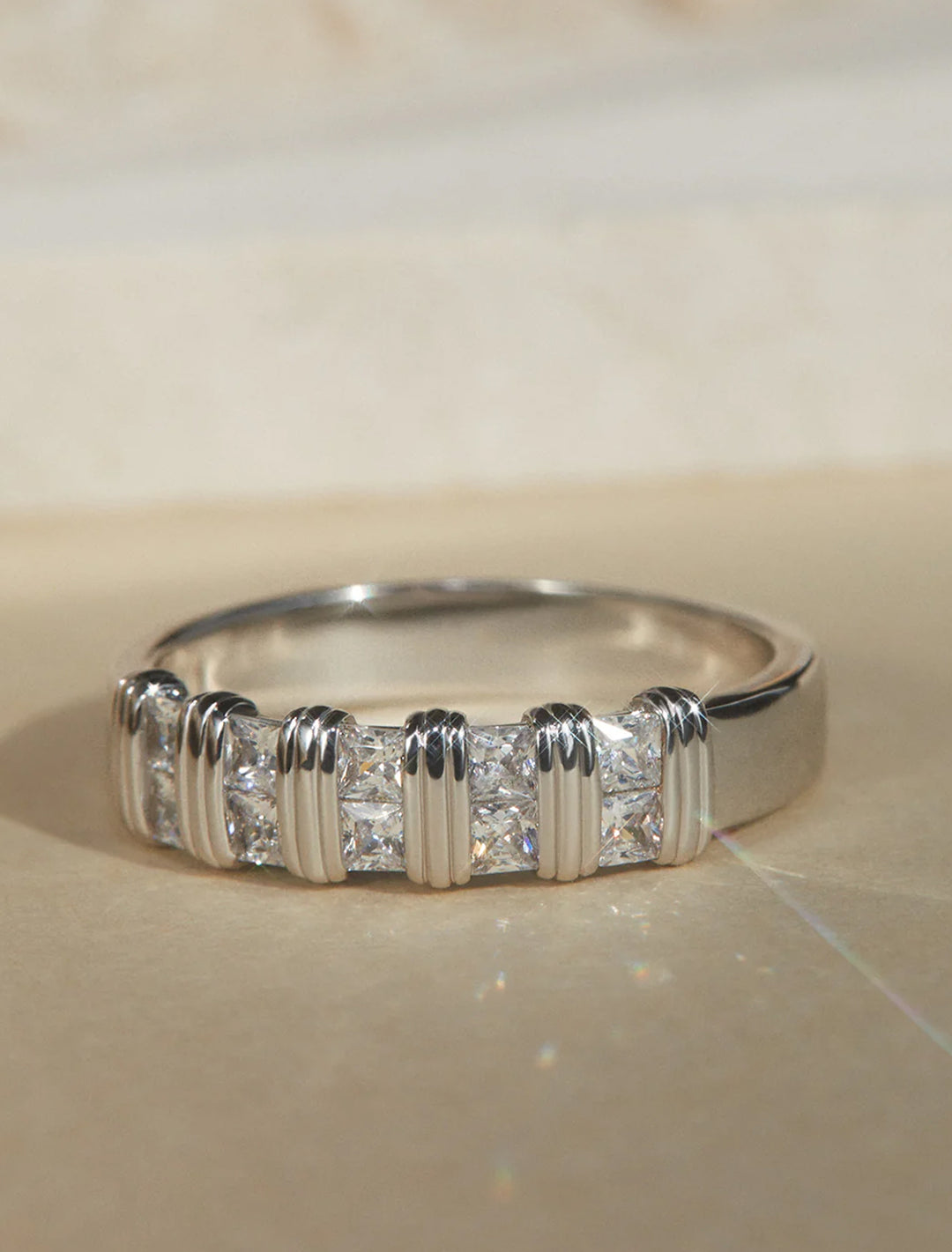 Stylized laydown of LUV AJ's remy princess cut band in silver.