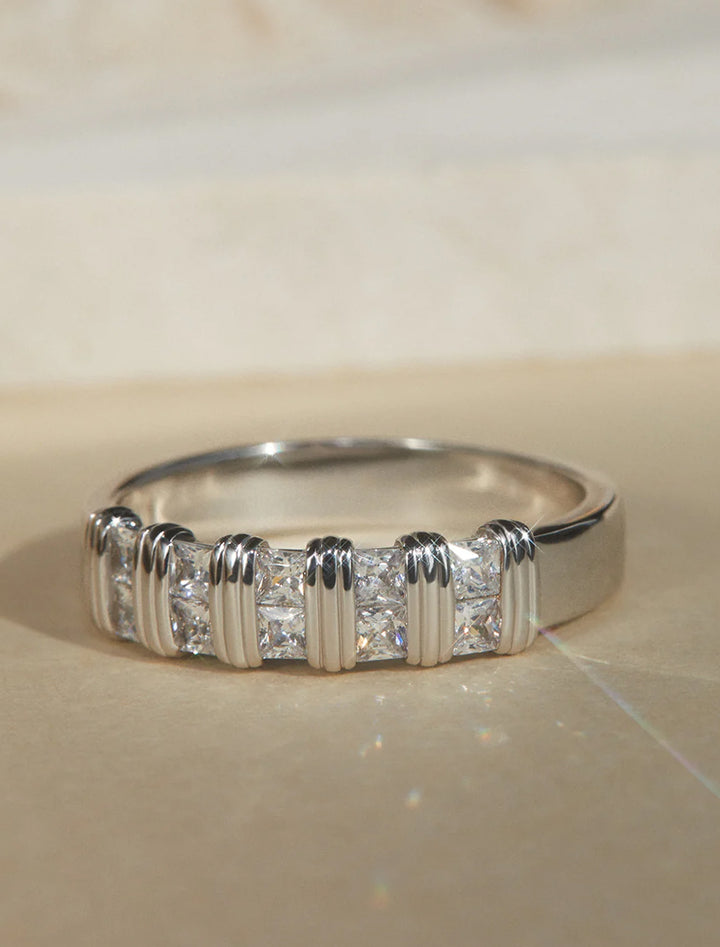 Stylized laydown of LUV AJ's remy princess cut band in silver.