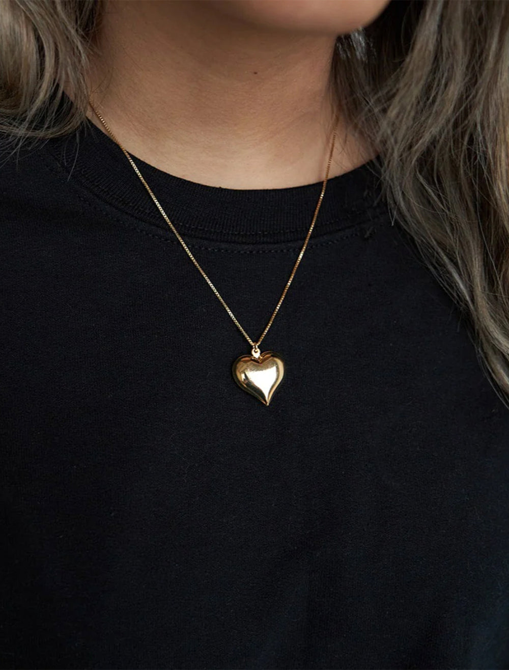 Model wearing Jonesy Wood's hart necklace in gold.