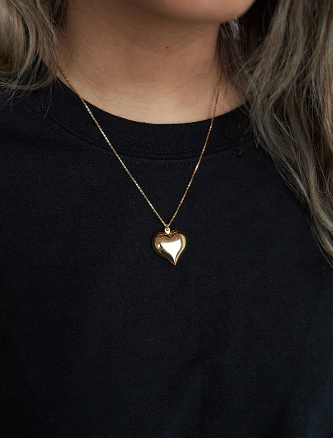 Model wearing Jonesy Wood's hart necklace in gold.