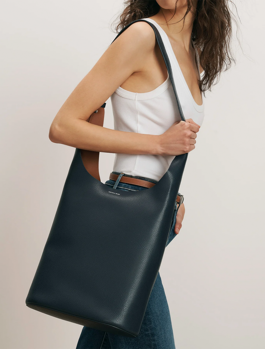 Model wearing Veronica Beard's large loop bag in navy and hazelwood leather.