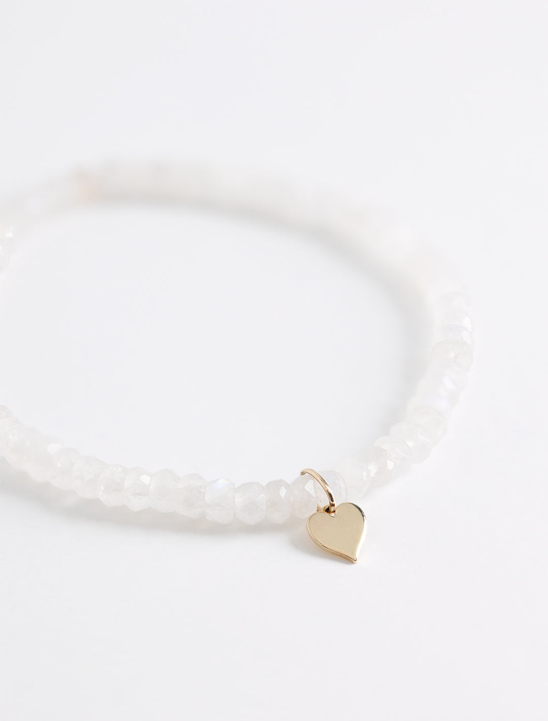 Close-up view of Sydney Evan's tiny pure heart charm on rainbow moonstone faceted rondelle.