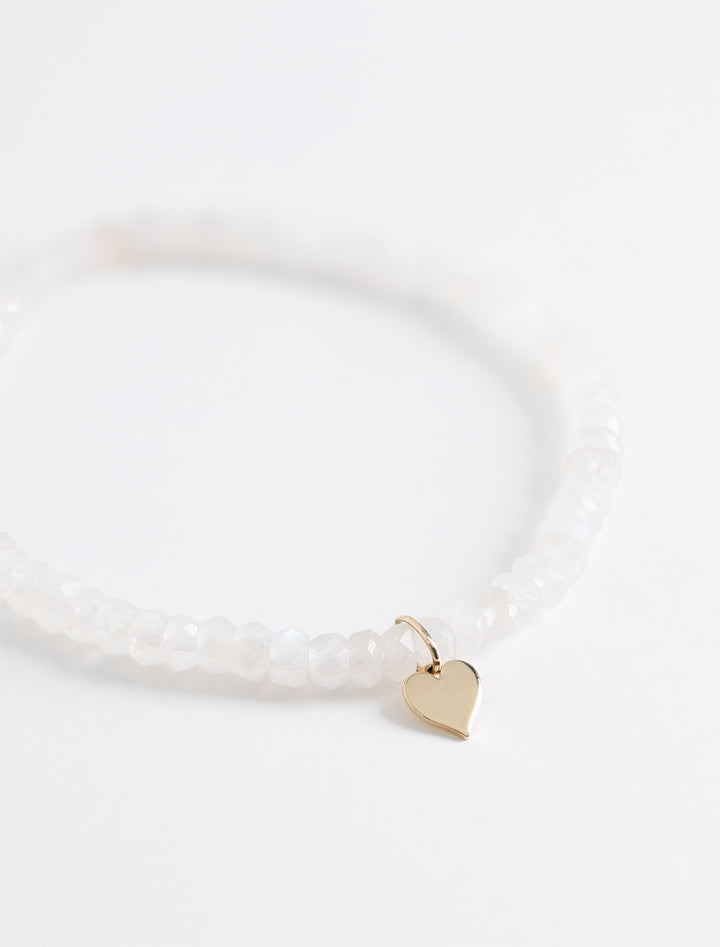Close-up view of Sydney Evan's tiny pure heart charm on rainbow moonstone faceted rondelle.