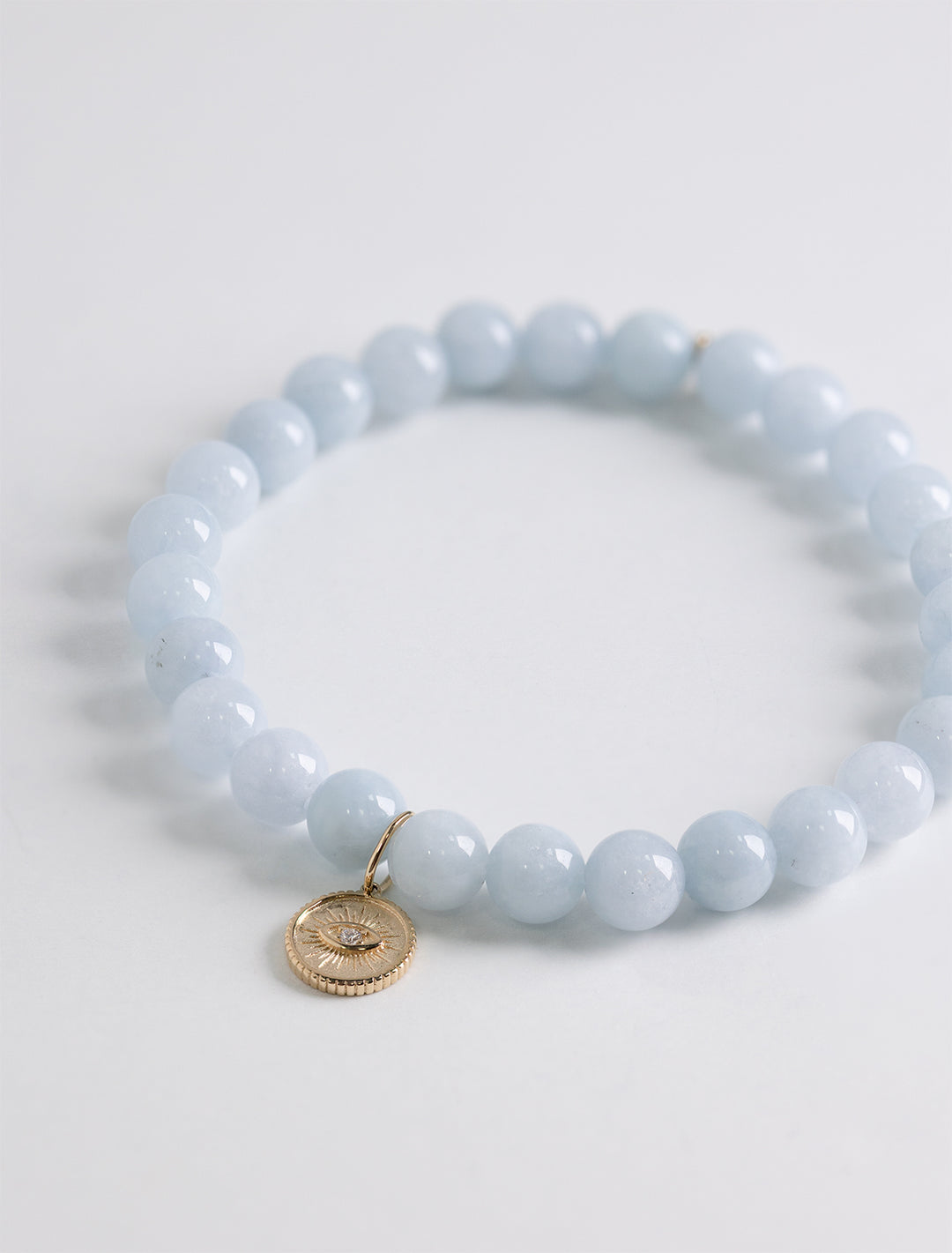 small marquise eye coin charm on aquamarine