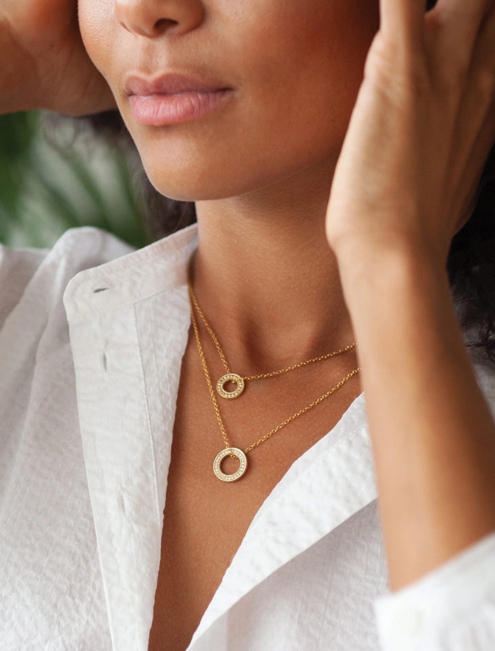 Model wearing Anna Beck's circle of life necklace in gold.