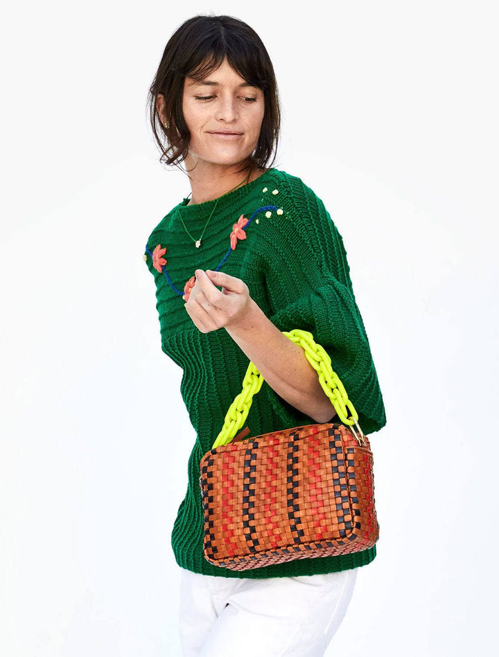 model carrying the marisol woven handbag in navy and cherry pinstripes with the shortie strap in neon yellow attached