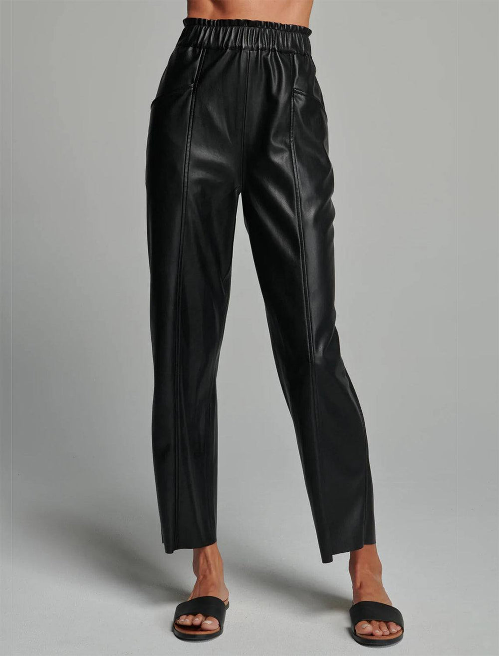 Model wearing Sunday NYC's Harper Pant in Black Vegan Leather. Model pairs the pants with black sandals.