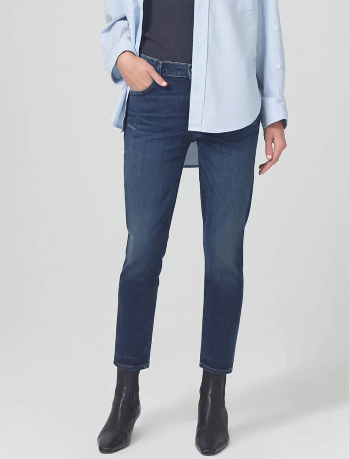 Model wearing Front view of Citizen of Humanity's Ella Mid Rise Jeans in Sky Lantern. Model pairs the jeans with a black tee, light blue button up shirt, and black heeled boots.