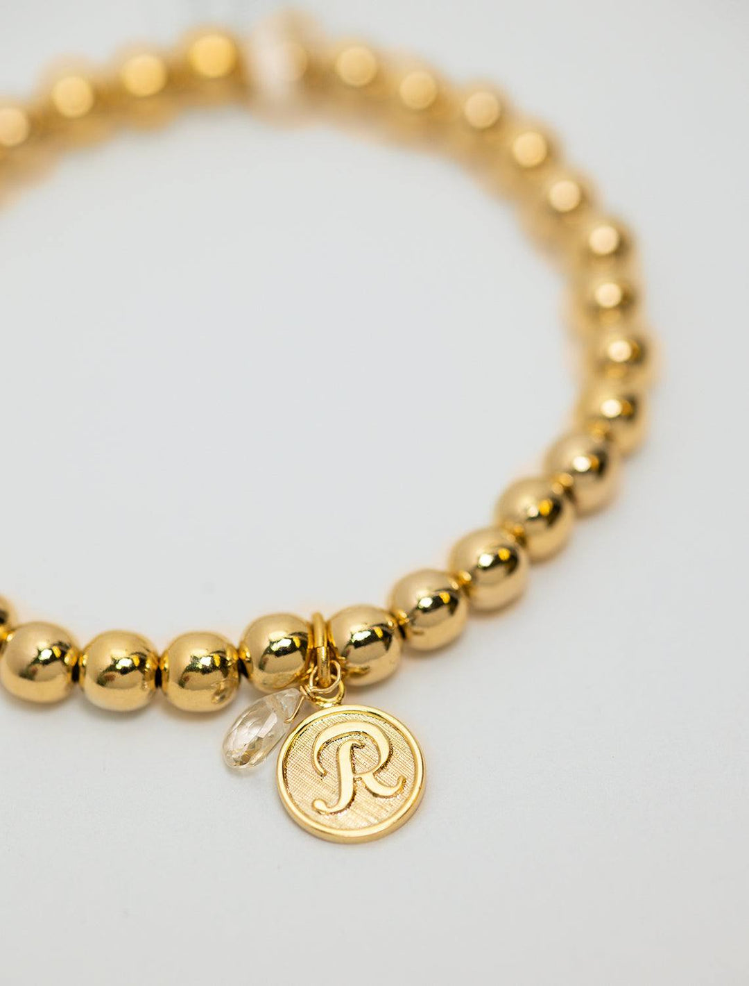 close up view of beaded monogram bracelet | R charm and gem
