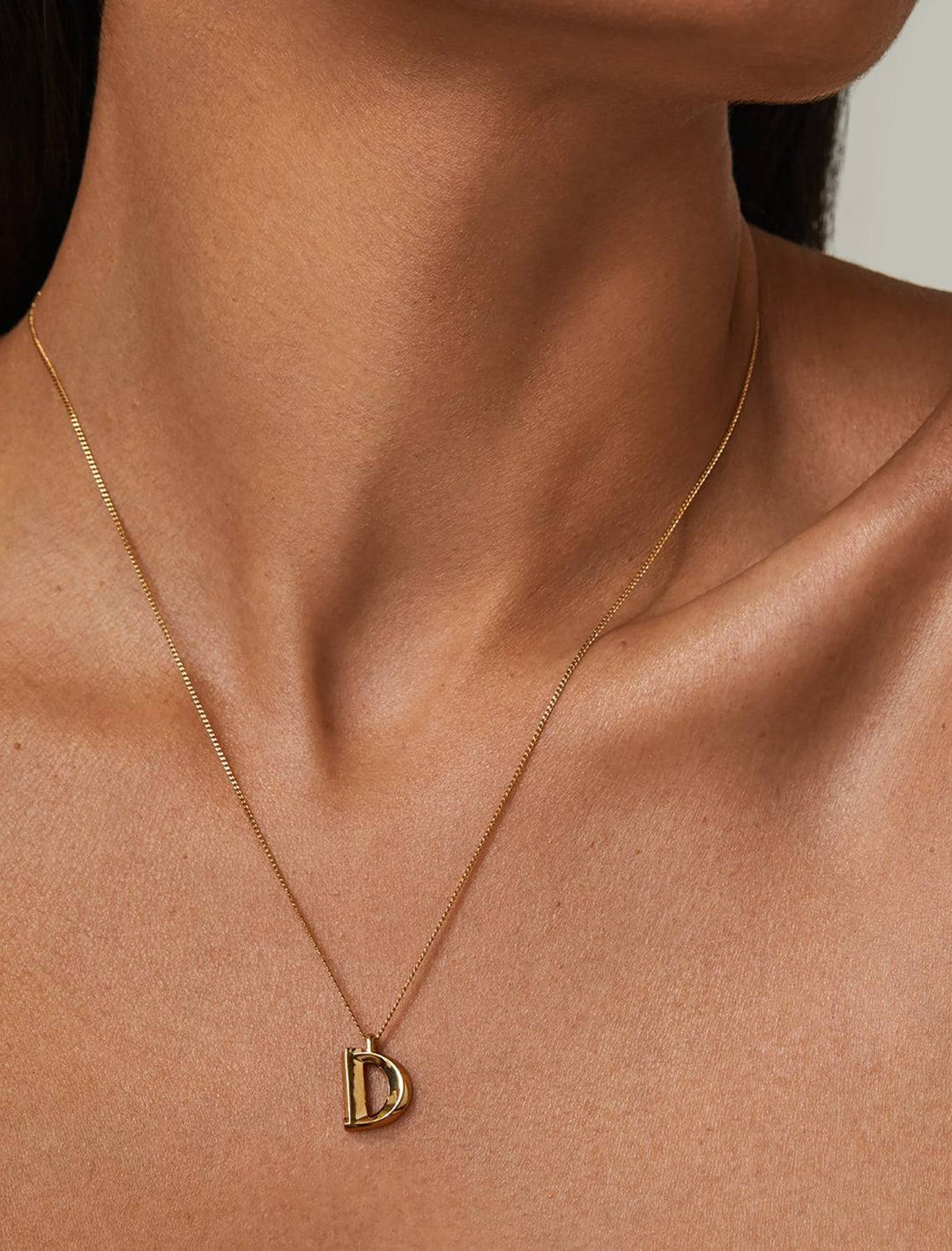 model wearing monogram necklace in gold | D